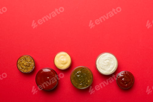 Preview: Different types of sauces in bowls on a colored Board . Top view. various sauces copy space