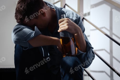 Preview: Addicted drunk man with alcoholic drink on stairs indoors