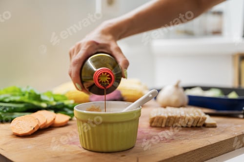 Preview: Closeup view of a woman pouring soya sauce into a cup