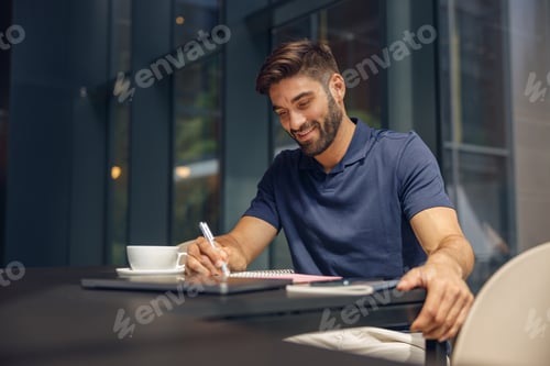 Preview: Male manager making notes in notepad during working day in modern office