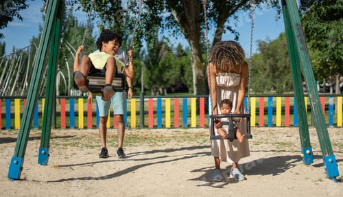 Preview: Latin mother and father swinging their children in a playground