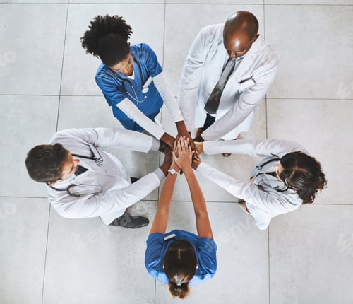 Preview: High angle shot of a diverse team of doctors joining their hands together in a hospital