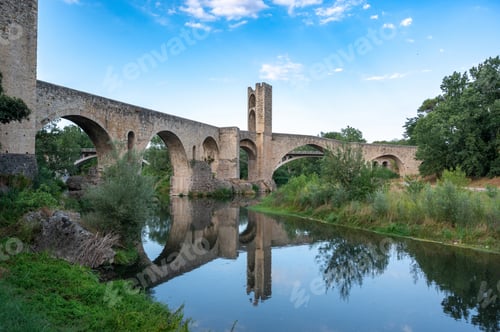 Preview: Besalú medieval bridge reflecting on fluvià river under blue sky