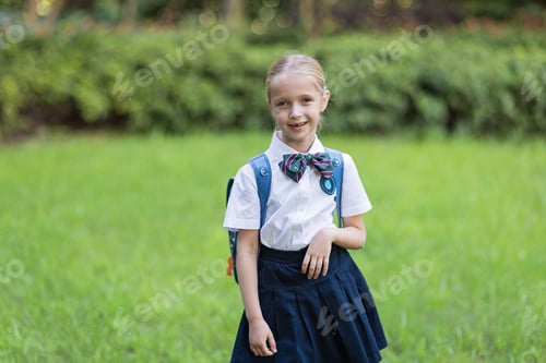 Preview: Schoolgirl back to school after vacations. Pupil in uniform and backpack early morning outdoor