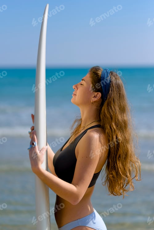 Preview: young woman with surfboard on the beach