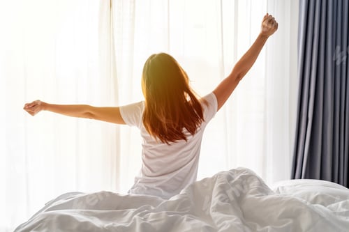Preview: Woman Stretching in Bed with Sunlight