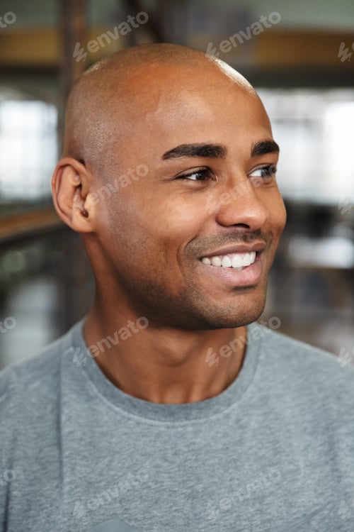Preview: Image of bald african american man smiling and looking aside indoors