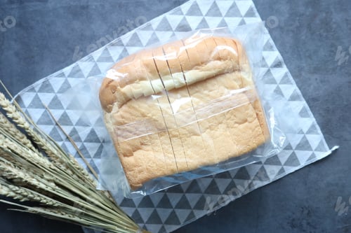Preview: top view of baked bread in a plastic packet on black background