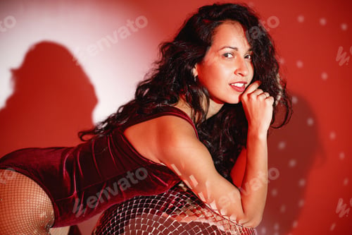 Preview: Young woman salsa dancer posing under a red projector's light