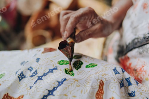 Preview: Close up picture of a person's hand drawing the design pattern of Indonesian batik tulis fabric.