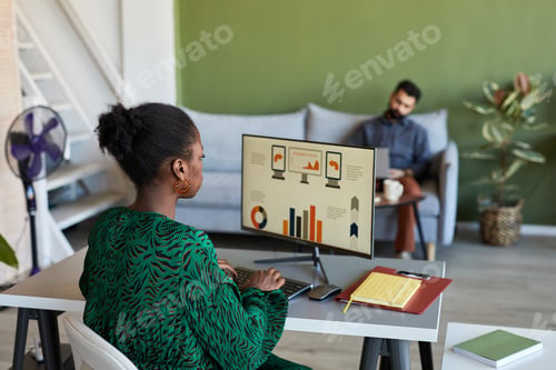 Preview: Young African American designer sitting in front of computer screen by workplace