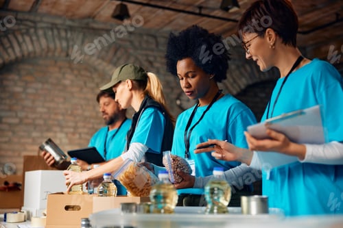 Preview: Multiracial group of volunteers packing donated food at humanitarian aid center.