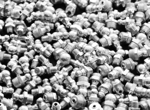 Preview: Closeup of various chrome hardware screws piled on each other on a black surface