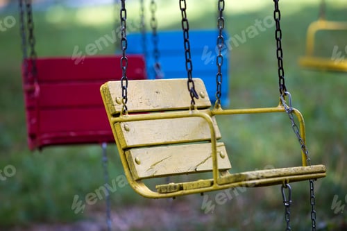 Preview: Close-up of empty wooden blue, yellow, vintage seats of multi-colored carousel hanging on chains.