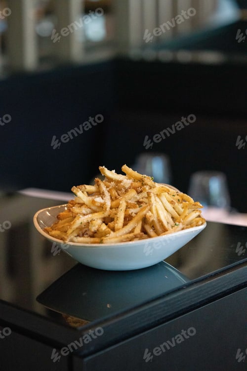 Preview: White plate full of golden-brown french fries placed on a white table countertop, ready to be served
