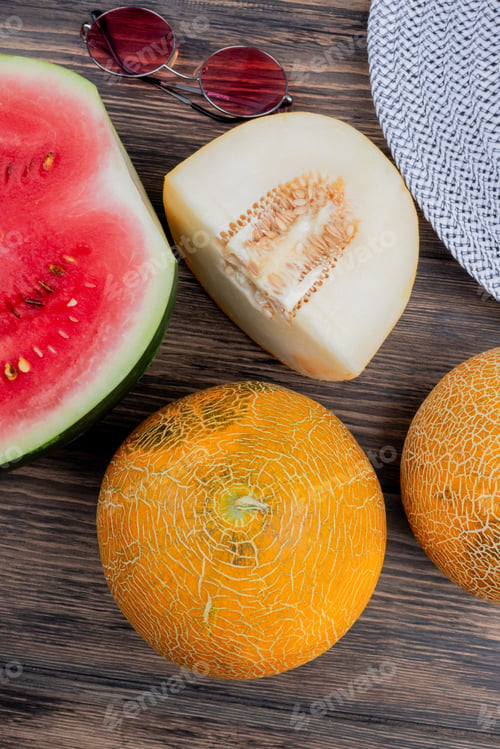 Preview: side view of whole and cut melons with watermelon half and glasses on wooden background