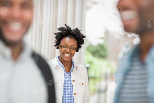 Preview: A woman looking at the camera, with two men in the foreground.