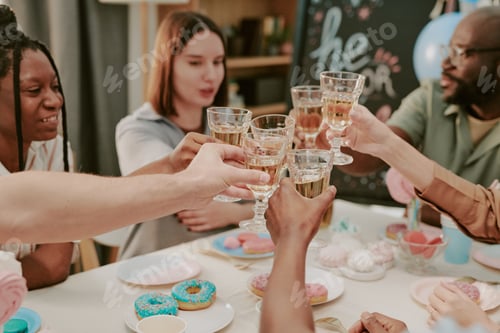 Visualização: Grupo diversificado de jovens adultos comemorando junto com copos de brinde