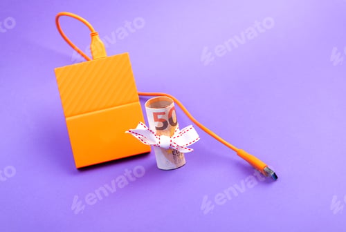 Preview: fifty euro banknote money roll tied with a white gift ribbon and external portable hard disk drives