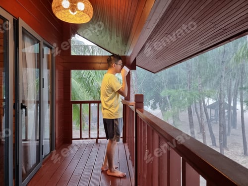 Preview: Portrait of an Asian gen z enjoying a cup of coffee from the resort hotel balcony
