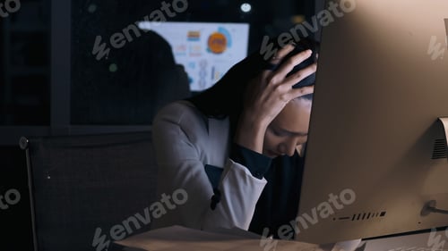 Preview: Stressed young Asian businesswoman working overtime at the office.