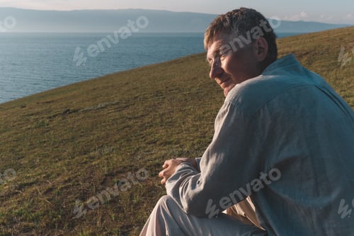 Preview: A candid portrait of a beautiful middle-aged man on the seashore against the background of water.