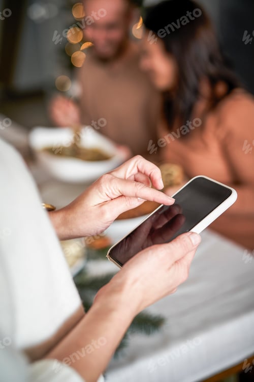Preview: Close up of woman using mobile phone at Christmas Eve