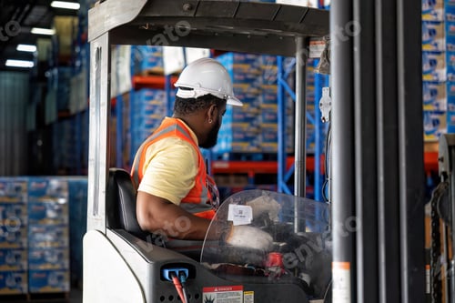 Preview: Forklift Truck Operator Lifts Pallet Cardboard Boxes On a Shelf by Trucks in Distribution Center