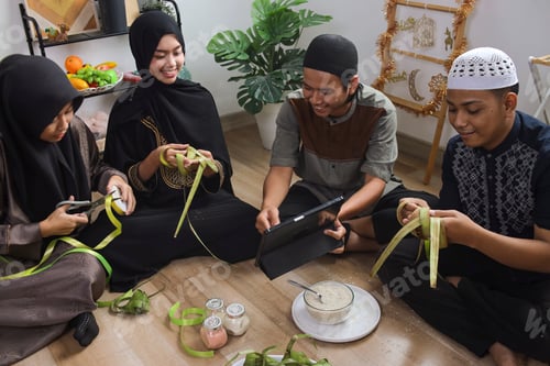 Preview: Group of Young Muslim People Sitting on Floor Weaving Palm Leaves for Making Ketupat on Eid Moment