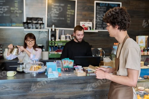 Preview: Coffee shop workers, a young guy in an apron in focus