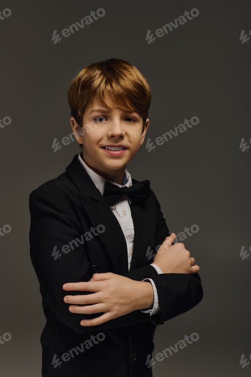 Preview: Stylish preteen boy poses confidently in elegant attire during studio fashion session