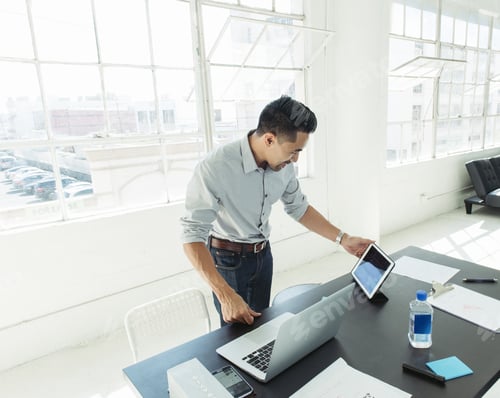Preview: Businessman working on laptop by office window