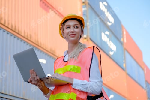 Preview: Portrait of beautiful technician use laptop in front of cargo containers with day light.