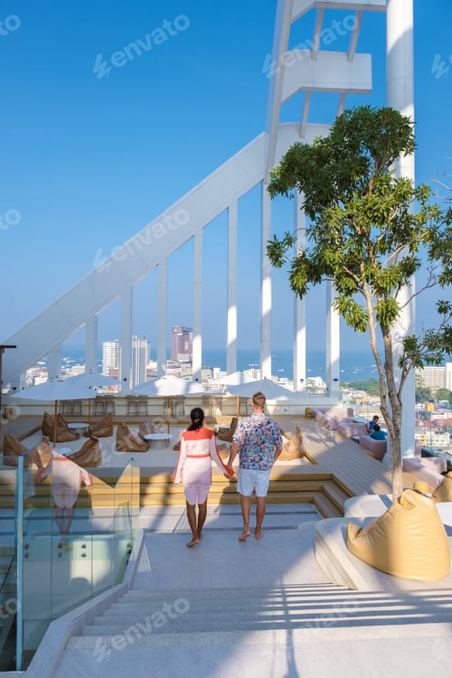 Vista previa: couple men and women having dinner during sunset at a rooftop restaurant looking out over the city