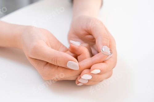 Preview: Woman holding contact lens on the finger tip.