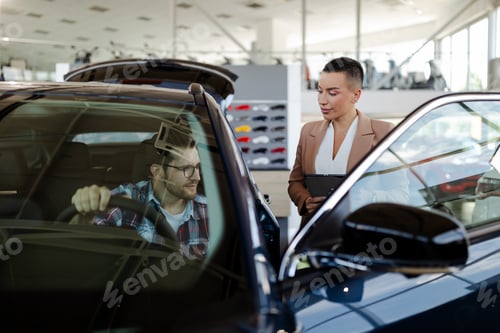 Preview: Top view of car buyer sitting in auto, choosing new automobile with seller In store.