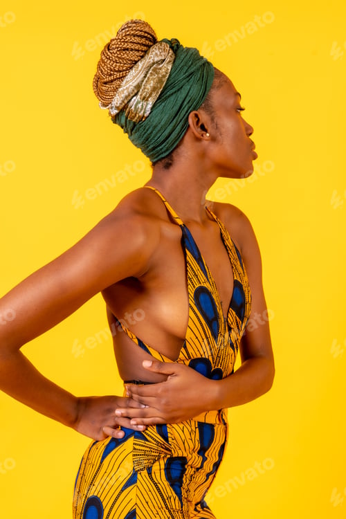 Preview: African young woman in the studio on a yellow background, traditional costume, looking to the right