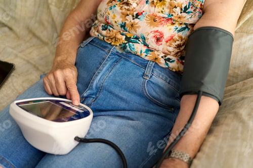 Preview: Unrecognizable Senior woman measuring her blood pressure at home. Hispanic Senior Woman Measuring