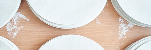 Preview: Wooden round coasters on light wooden surface with white chalk traces