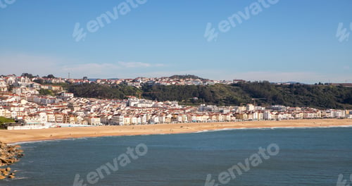 Preview: there is a large beach with houses on the hill in the background