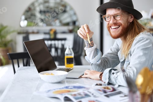 Preview: Positive bearded hipster male eats french fries with orange juice, chats on dating site, looks at la