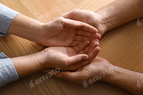 Preview: Young people holding hands on wooden background, top view. Happy family