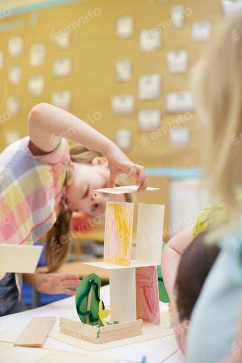 Preview: Primary schoolgirl making a cardboard structure on classroom desks