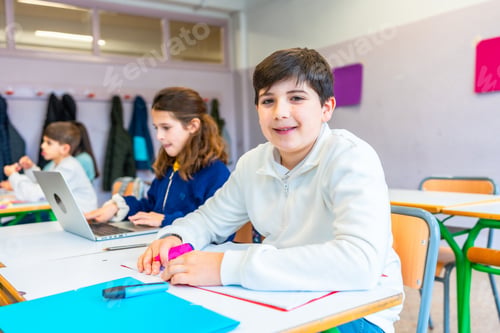Preview: Elementary school students studying in classroom, using laptop and colorful markers