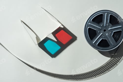 Preview: top view of 3d glasses with shadow and film reel with twisted cinema tape on grey background