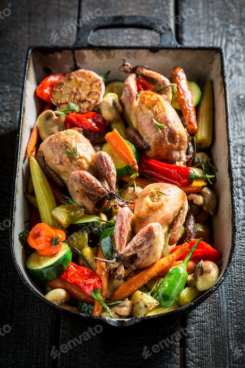 Preview: Grilled quails with vegetables in casserole on dark background