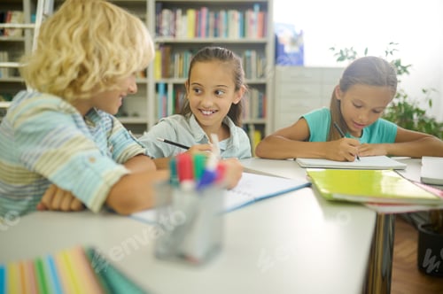 Preview: Girl looking at boy writing at table