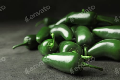 Preview: Pile of green hot chili peppers on grey table, closeup. Space for text