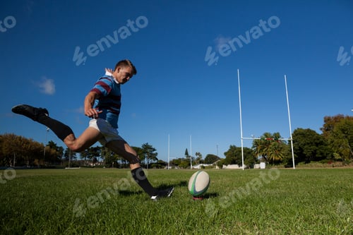 Preview: Full length of rugby player kicking ball for goal