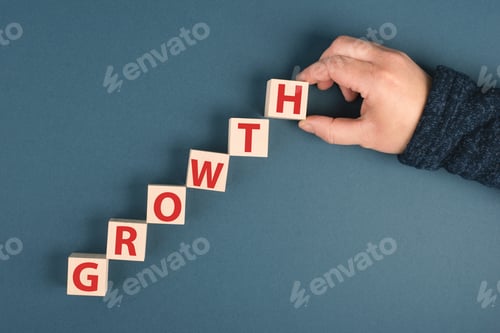 Preview: The word growth is standing on wooden cubes,hand is putting the last letter to the row